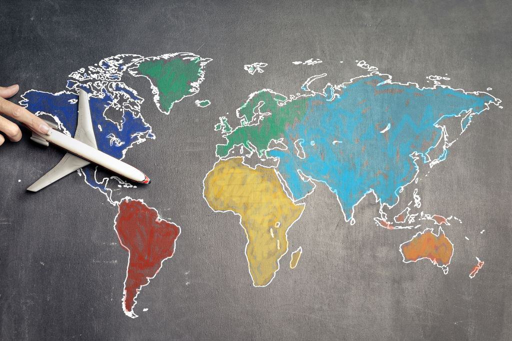 A plane flying over colourful world map drawn on a chalkboard