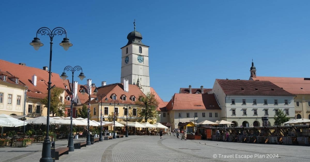 pretty square with a clock tower and restaurant terraces in the city of Sibiu 