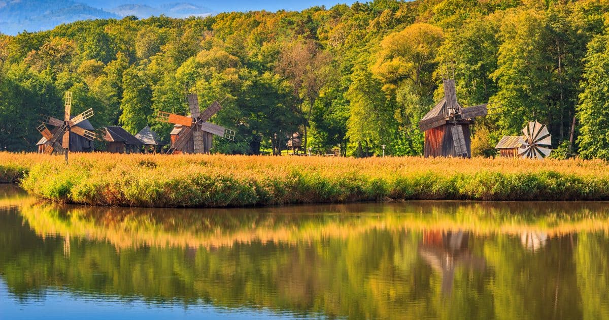 historic wooden windmills in a grassy area by a lake in the Astra Museum, Sibiu