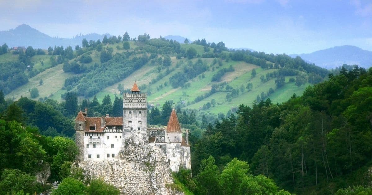 medieval Bran Castle with green rolling hills in the background