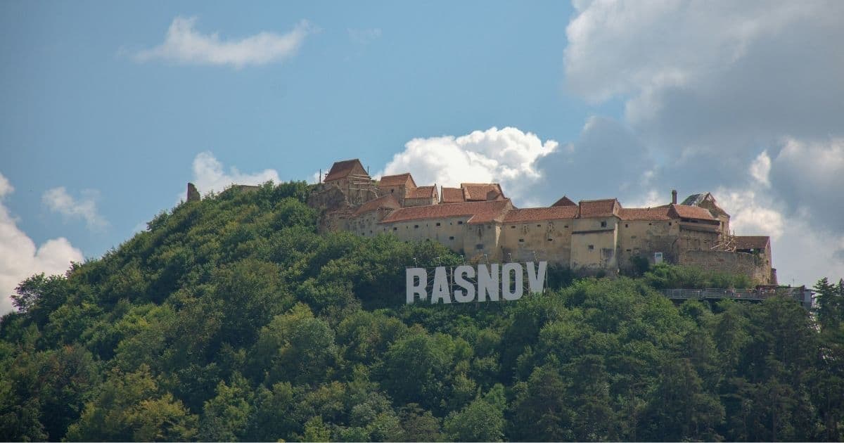 giant Rasnov sign in front of the medieval citadel on top of a hill