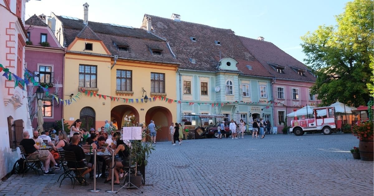 colourful houses and restaurant terraces in Citadel Square, Sighisoara