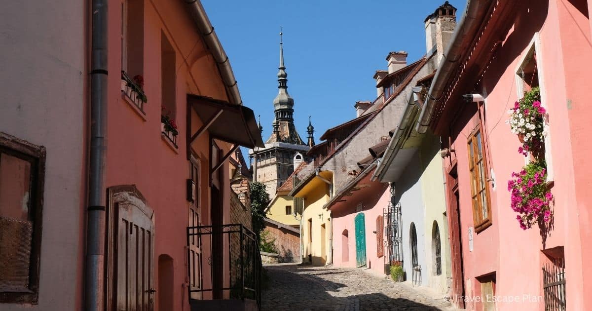street lined with colourful houses leading to the clock tower in Sighisoara, Romania