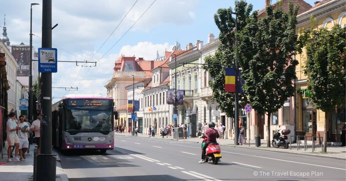 a street in Cluj-Napoca featuring a local bus and motorcyclist 