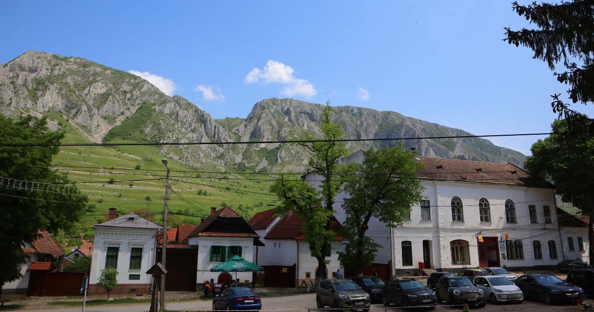 historic white houses with green window shutters in Rimetea village against mountain backdrop